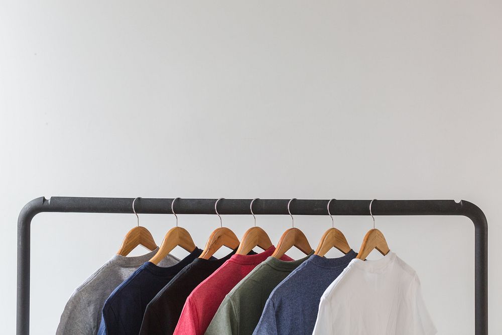 T-shirts hanging on wooden hangers.