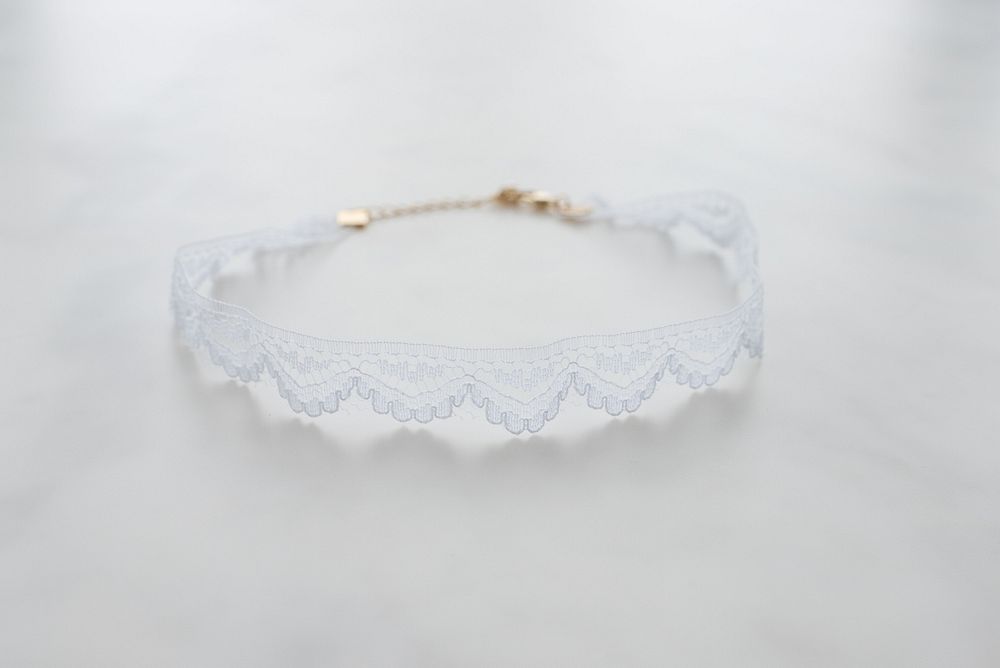 Close up of white lace choker with gold chain fastener.