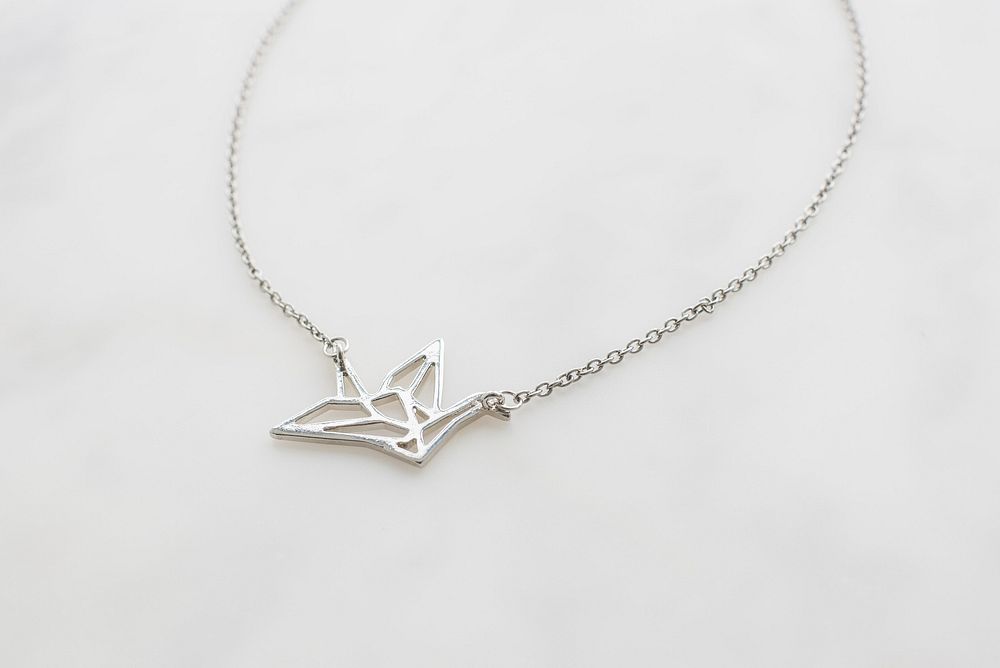 Close up of silver origami crane necklace.