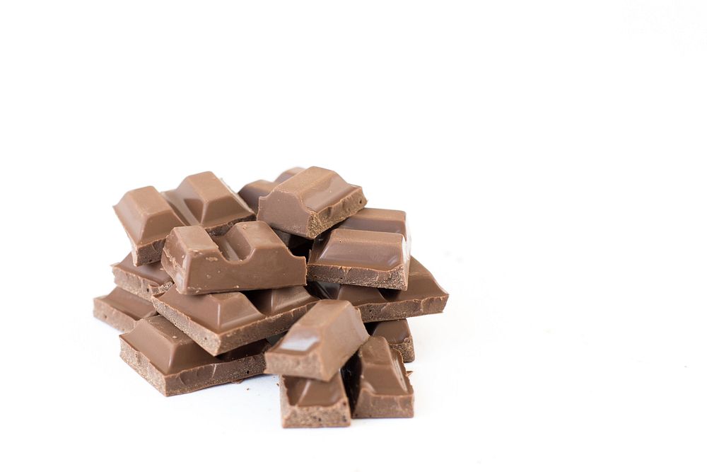 A pile of milk chocolate pieces against a white background.