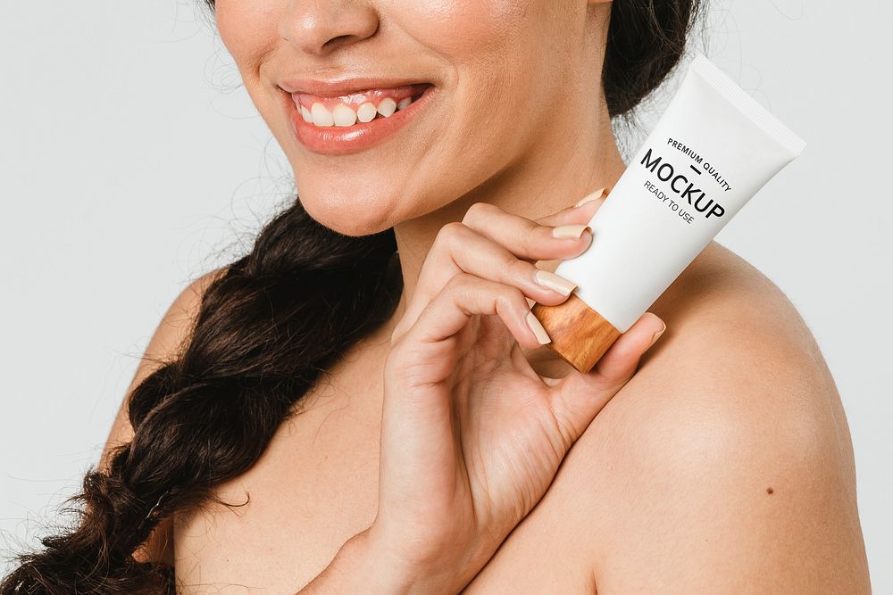 Cheerful woman holding a skin care product mockup