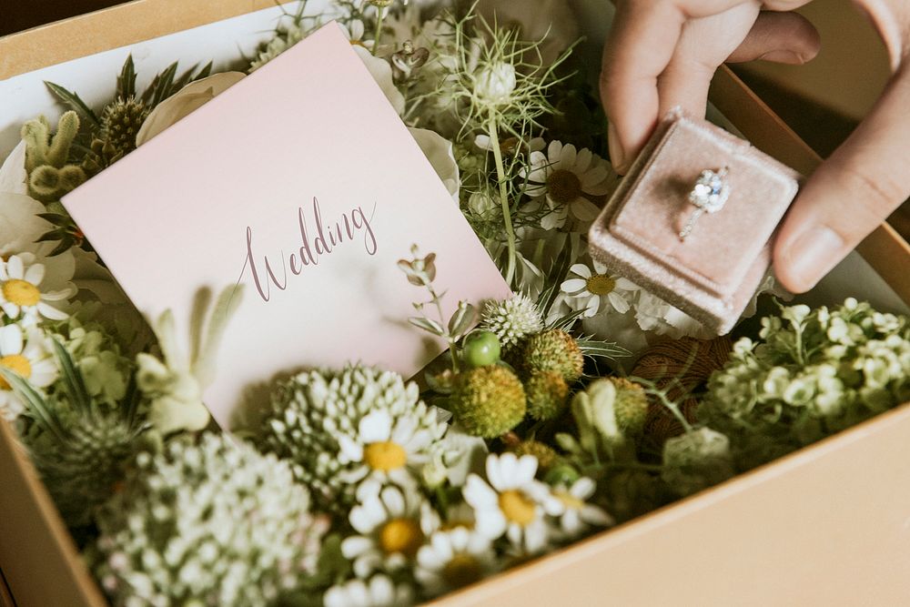 Box filled with various flowers and a wedding ring