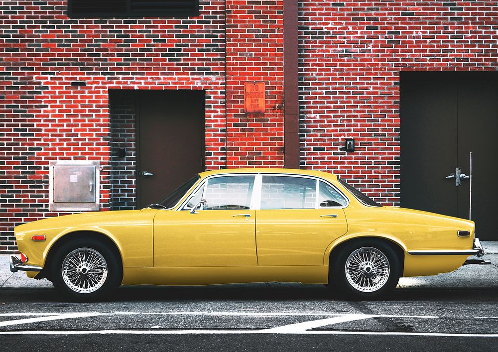 Yellow classic car in front of brick building