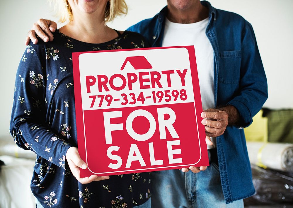 Couple with a property for sale sign