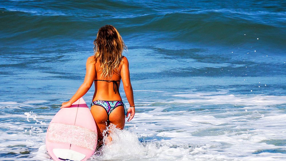 Woman surfer in bikini standing in the sea, free public domain CC0 photo.