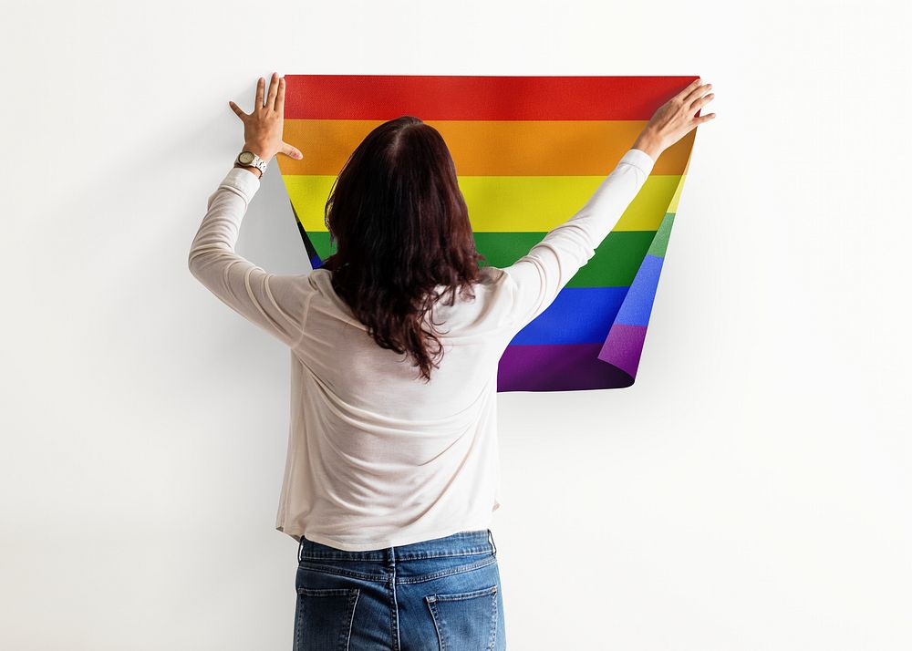 Pride flag background, woman decorating wall