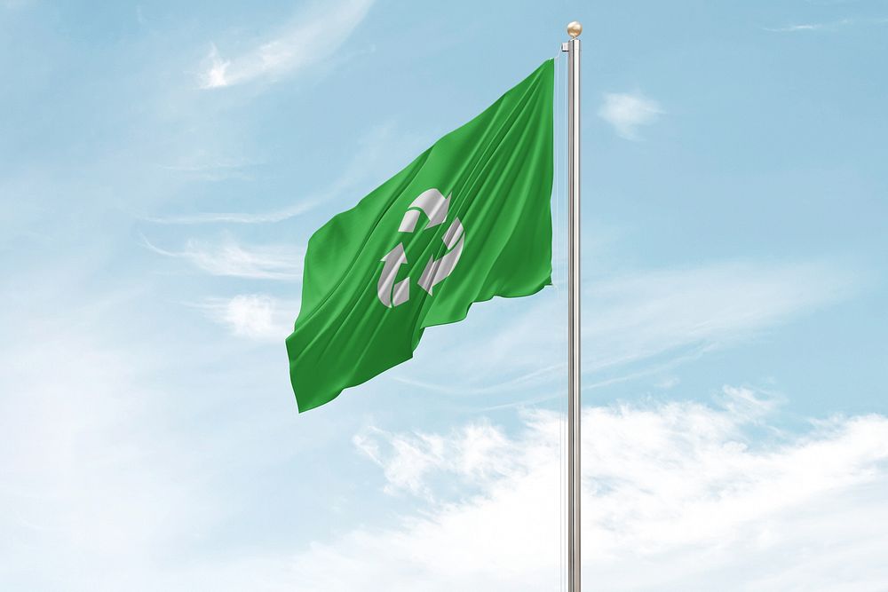 Green recycling flag on pole sky background