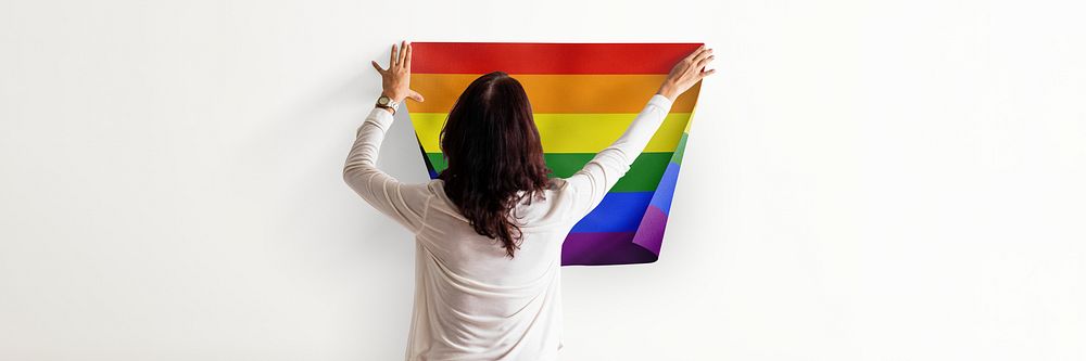 Pride flag background, woman decorating wall