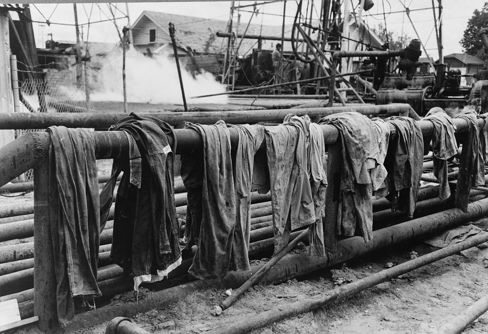 Clothing of oil drilling workers drying on steam pipe, Kilgore, Texas by Russell Lee
