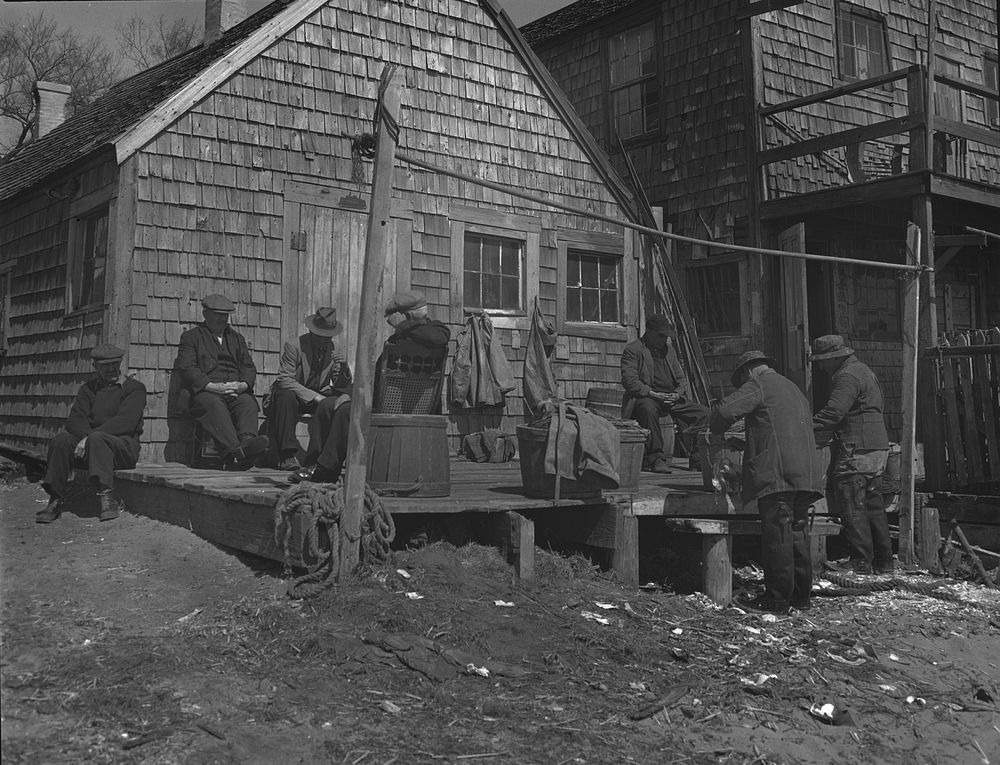 Provincetown, Massachusetts. Portuguese dory fisherman gossiping in front of their fishing shack, where they store their…
