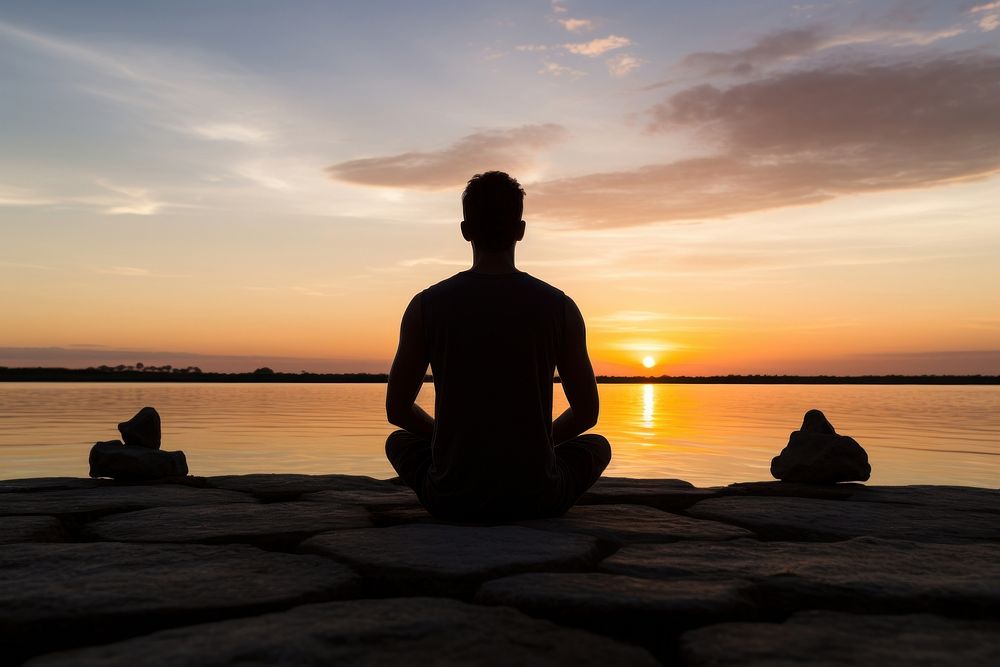 Backlighting silhouette meditating sunset. 