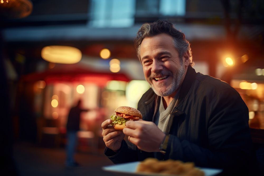 An middle aged man eating burger food portrait biting. 