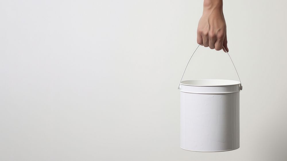 Hand carrying a paint bucket container lighting standing. 