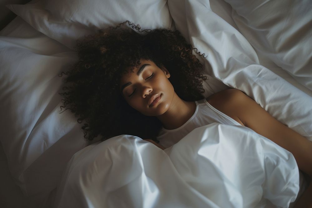 photos of a black woman lying on the side sleeping in white bed. 