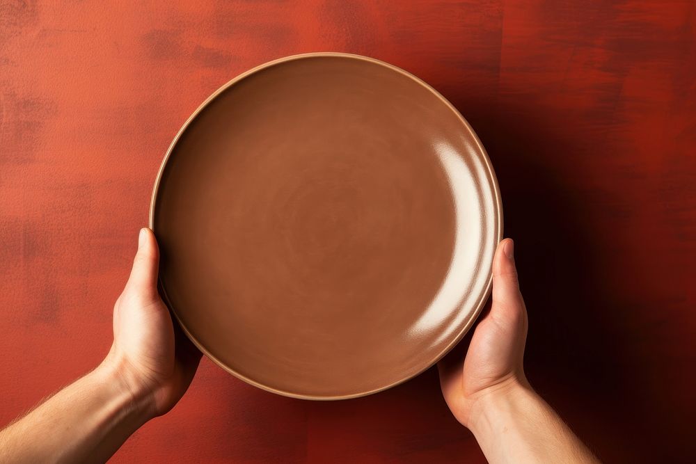 Hands holding a plain plate brown bowl hand. 