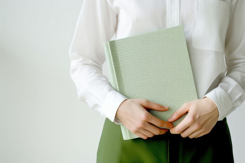 Hand holding a green notebook publication pattern person. 