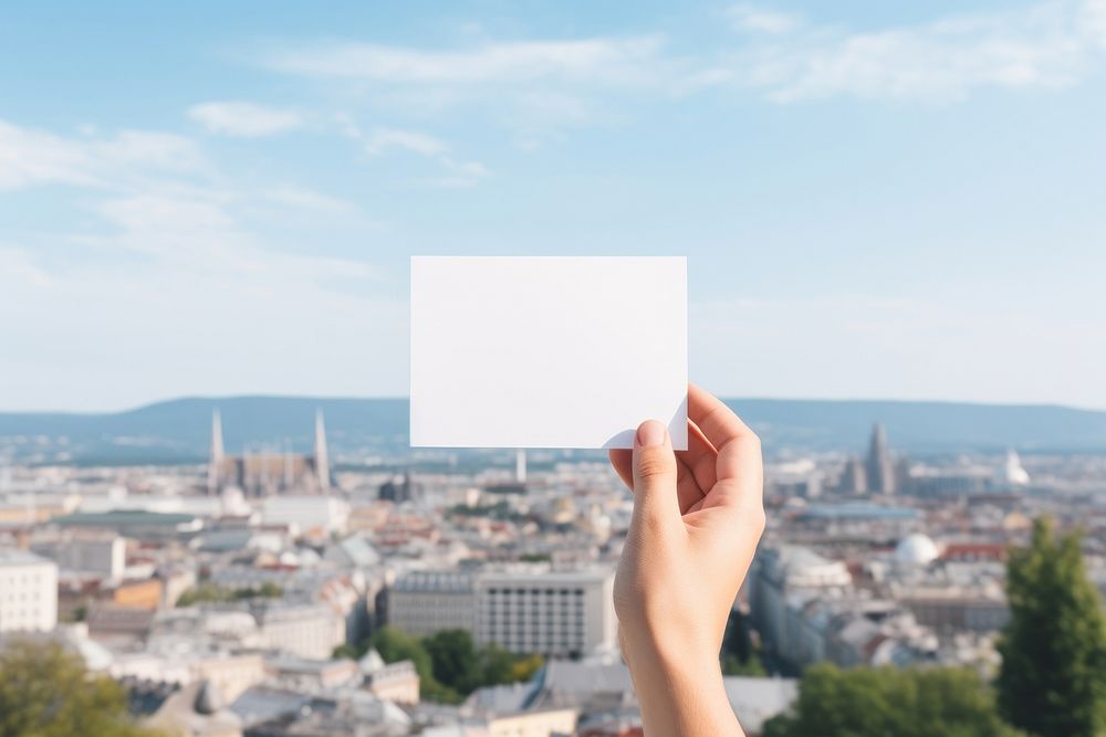 Hand holding white card architecture cityscape building. 