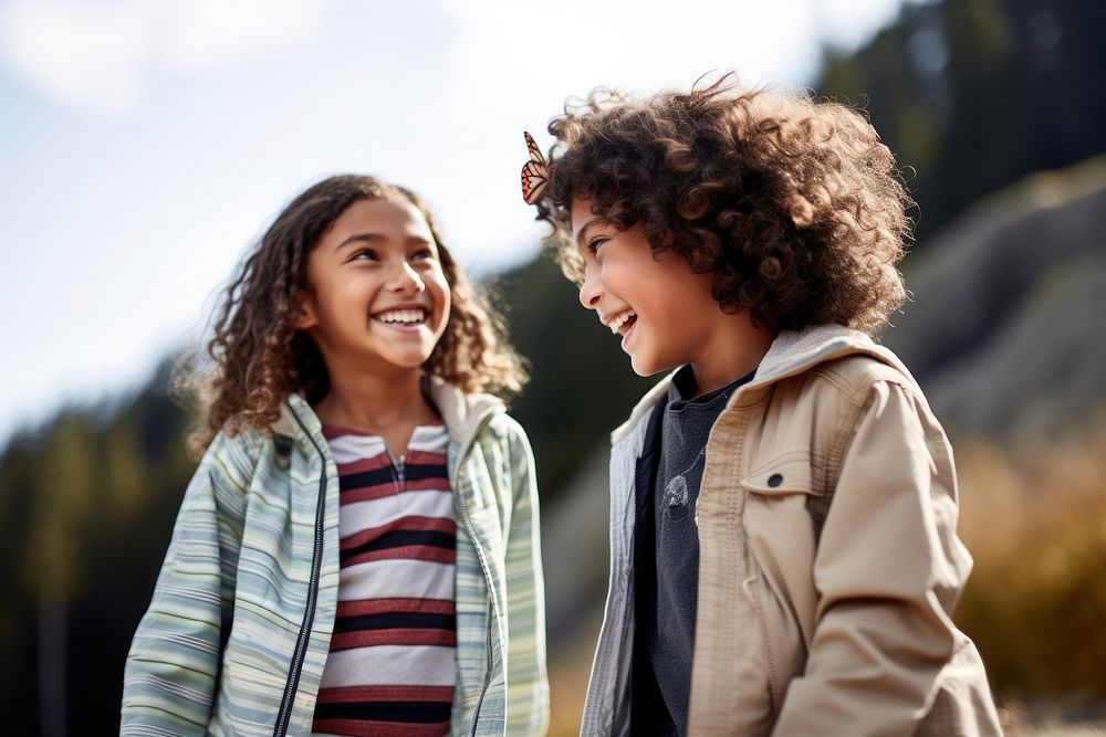 Two diversity kids watching a butterfly smile fun togetherness. 