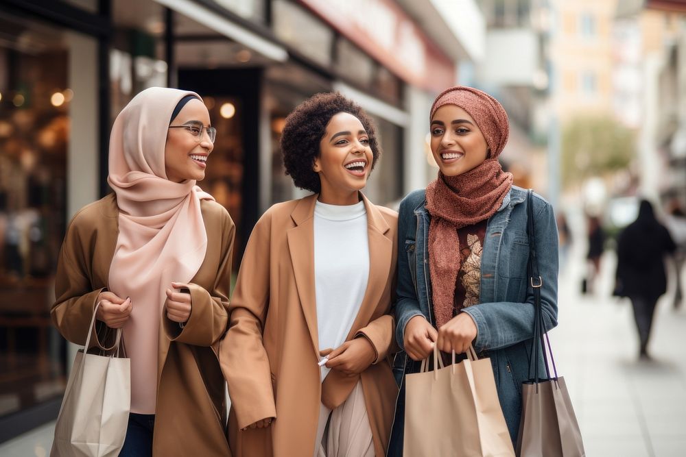 Three Muslim young adult woman shopping together laughing scarf happy. 