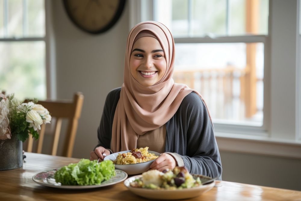 Muslim woman smiling eating plate. 