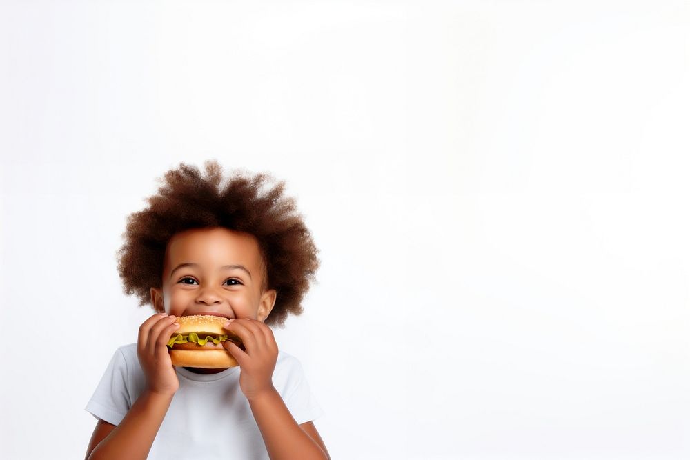 Cute little african boy enjoy eating a hamburger have fun biting cute food. 