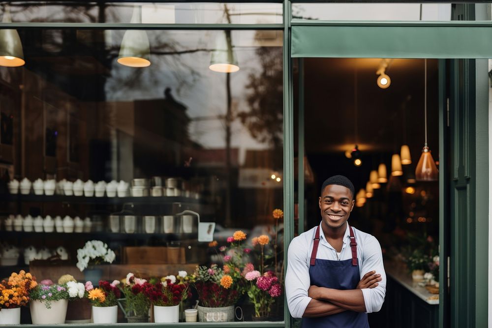 Photo of a cheerful small business owner standing and smiling in front of their shop.  