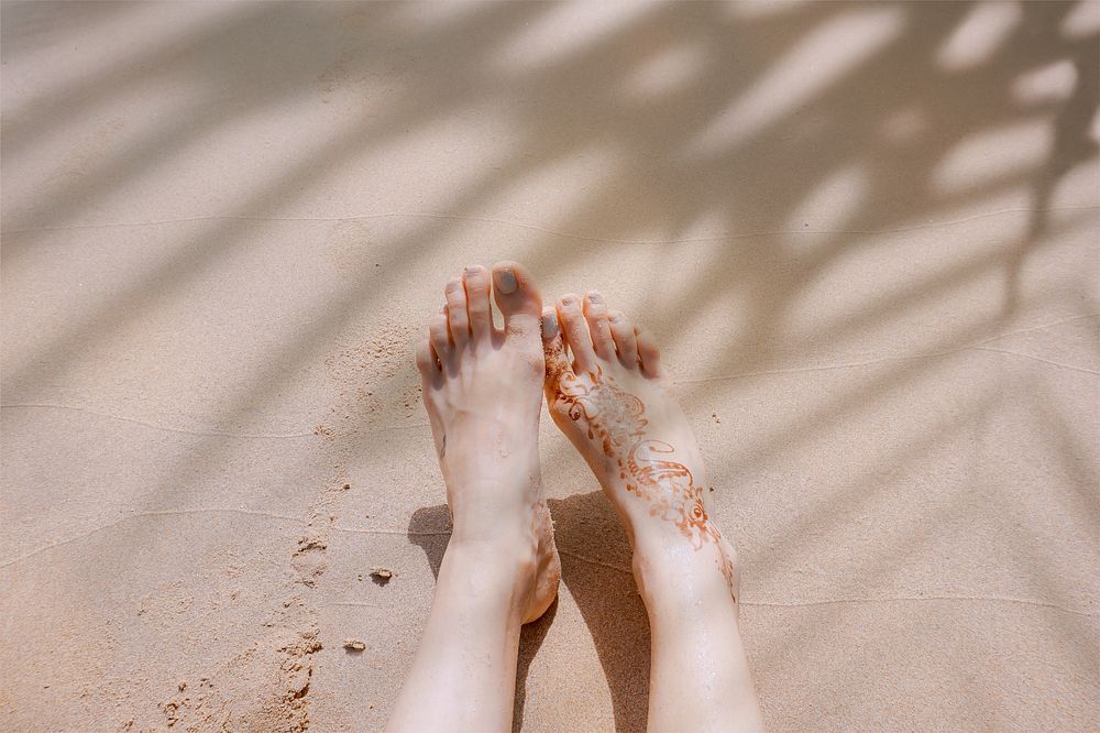 Woman on beach, palm leaf shadow