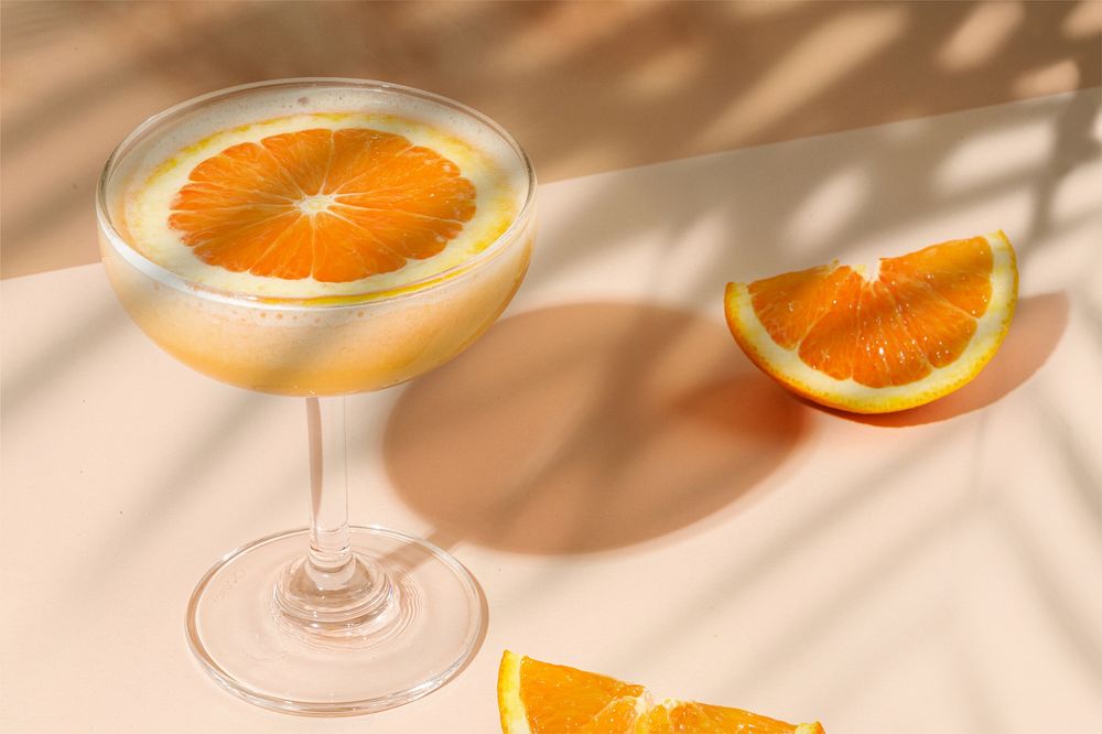 Orange cocktail drink, palm leaf shadow
