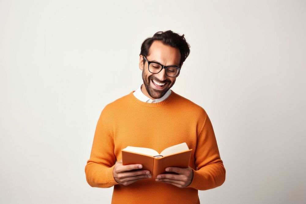 Man hold read Brown textbook beaming shiny smile enjoy wear spectacles orange pullover portrait sweater reading. AI…
