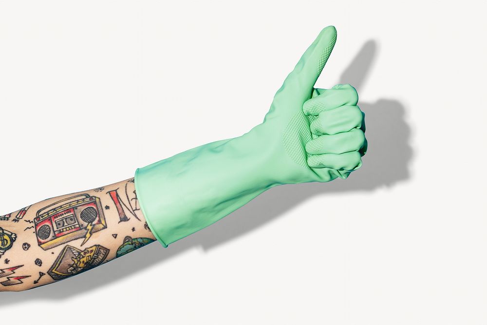 Tattooed hand wearing gloves showing thumbs up gesture isolated image