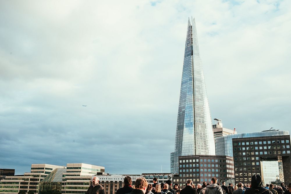 A small crowd of people at the bottom of the image gives perspective on the huge, "Shard" skyscraper in London, England. It…