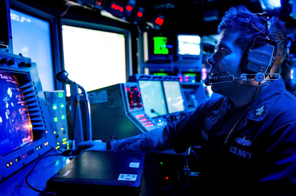 U.S. Navy Fire Controlman 1st Class Aaron Tadlock monitors a radar console in the combat information center aboard the…