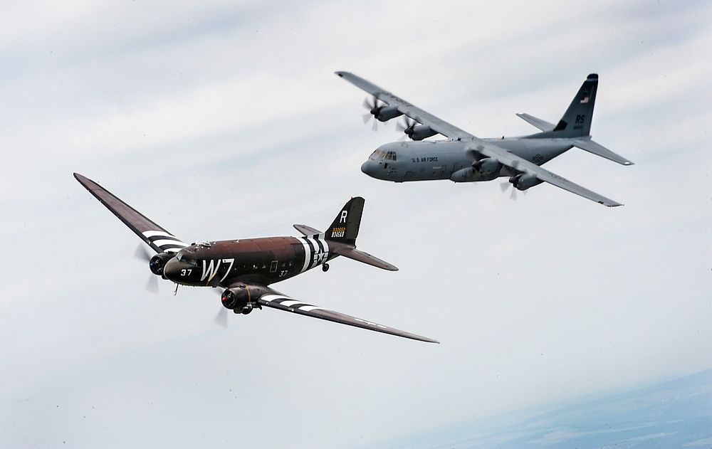 A former U.S. Air Force C-47 Skytrain aircraft, left, flies alongside a C-130J Super Hercules aircraft assigned to the 37th…