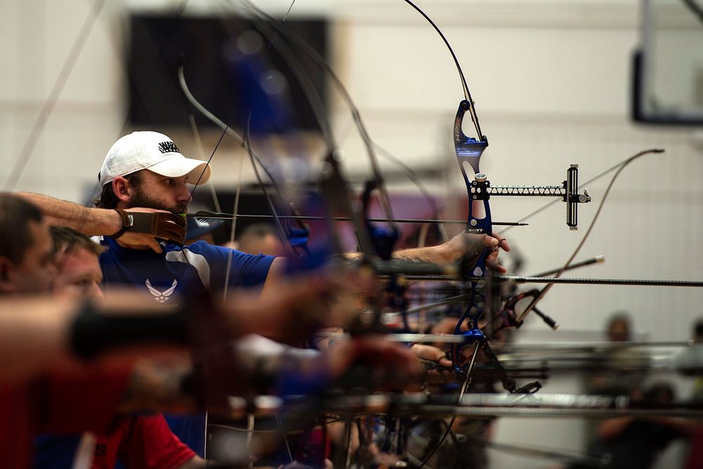 U.S. Air Force veteran Ryan Gallo, center, aims his bow in the archery qualification match during the 2014 Warrior Games in…