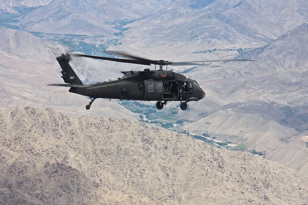 A UH-60 Black Hawk helicopter assigned to Task Force Eagle Assault, 5-101 Combat Aviation Brigade, flies over the rugged…
