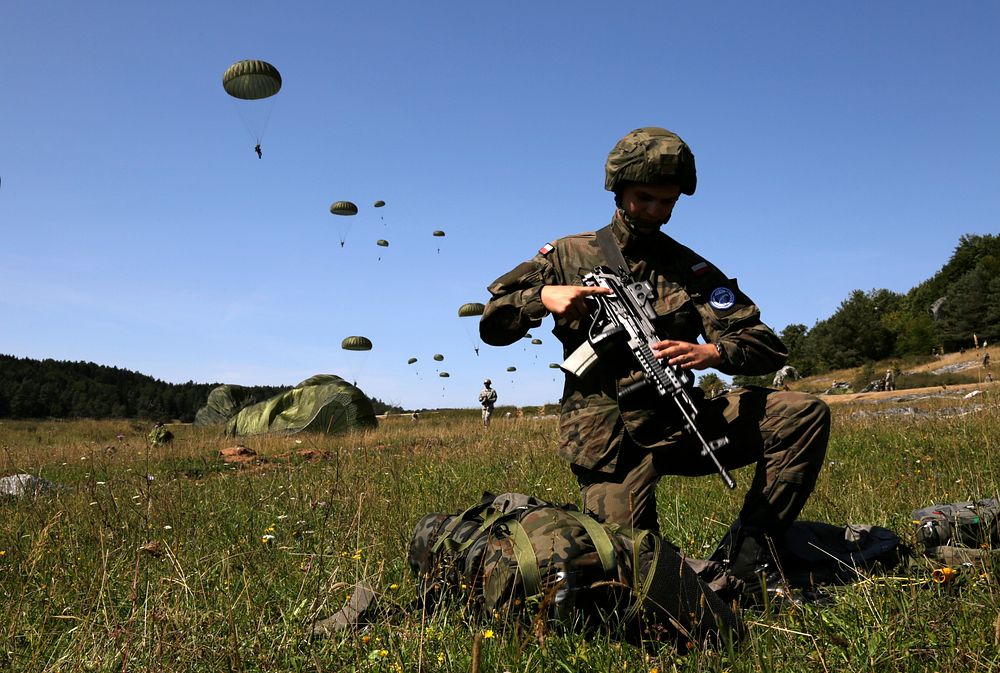 A Polish paratrooper with the 6th Polish Airborne Brigade, unpacks his backpack after parachuting out of a plane during…