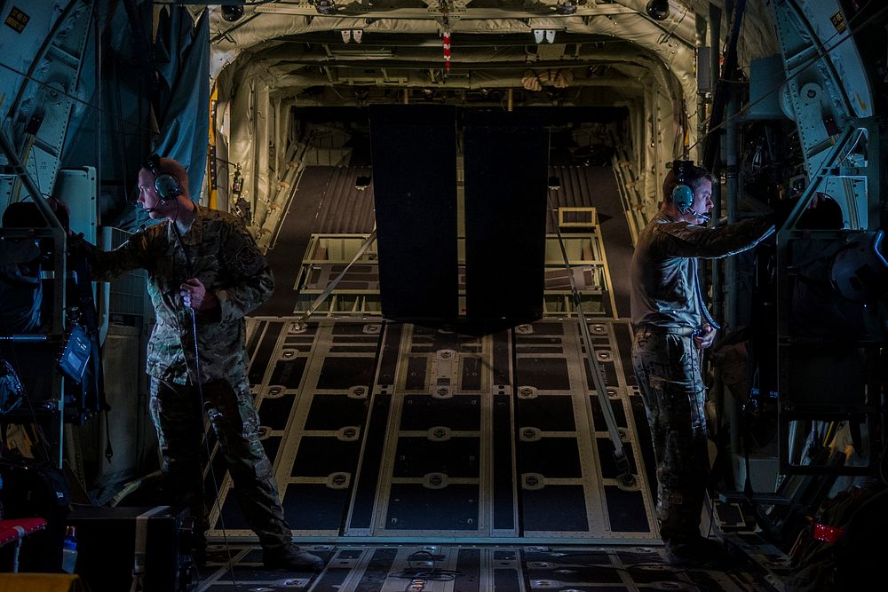 Two Airmen, assigned to the 71st Rescue Squadron at Moody Air Force Base, Ga., look out the windows of a C-130J Hercules…