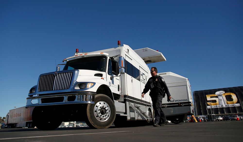 A U.S. Customs and Border Protection non-intrusive inspection vehicle waits on the parking lot to begin scanning a line of…