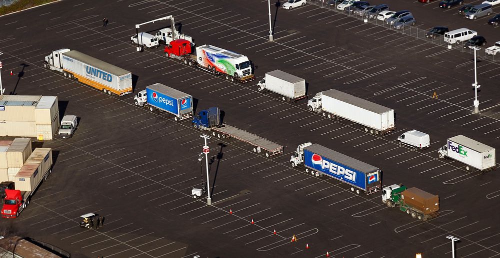 Trucks line up on a parking lot to be x-rayed by a U.S. Customs and Border Protection non-intrusive inspection vehicle, top…