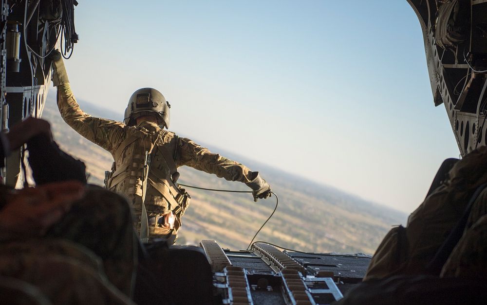 A U.S. Army aircrewman sits at the rear hatch of a CH-47 Chinook helicopter during a transit from Baghdad International…