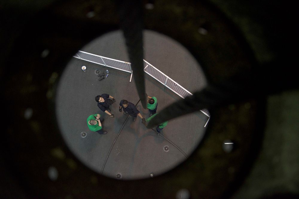 U.S. Sailors feed a cable to engine room one from the hangar bay of the aircraft carrier USS Dwight D. Eisenhower (CVN 69)…
