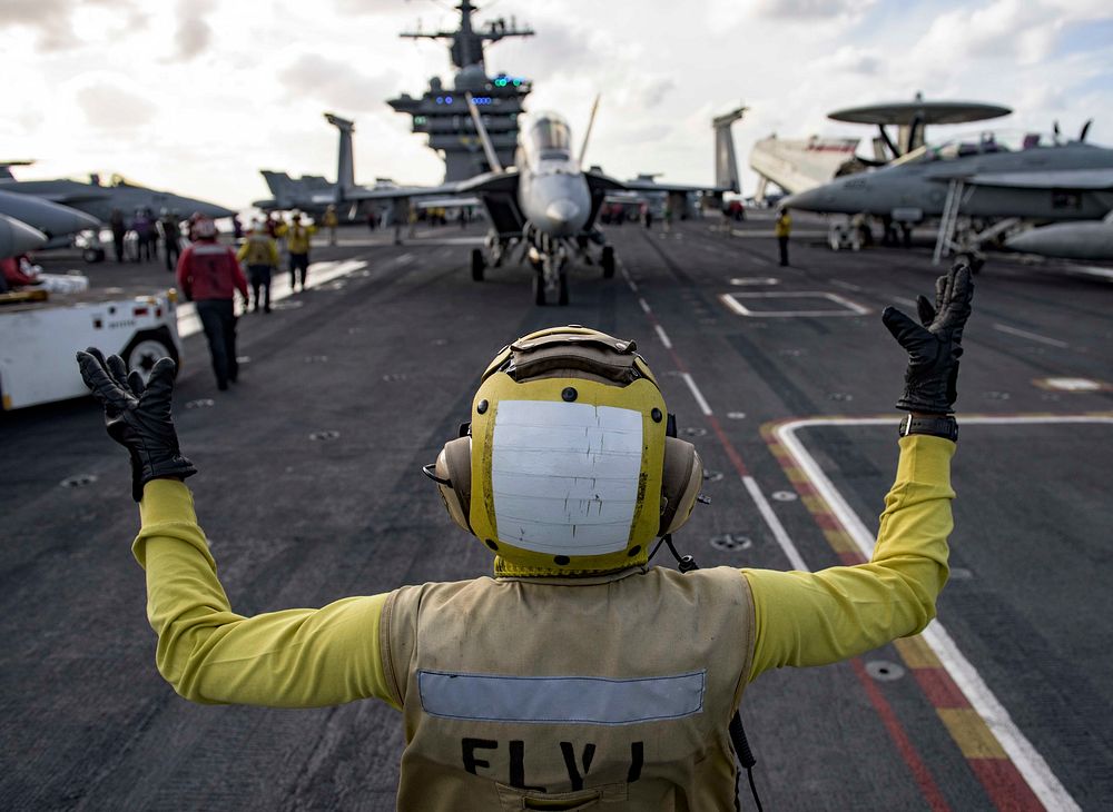 U.S. Navy Aviation Boatswain’s Mate (Handling) 2nd Class Keyonnia Cook directs an F/A-18F Super Hornet attached to the…