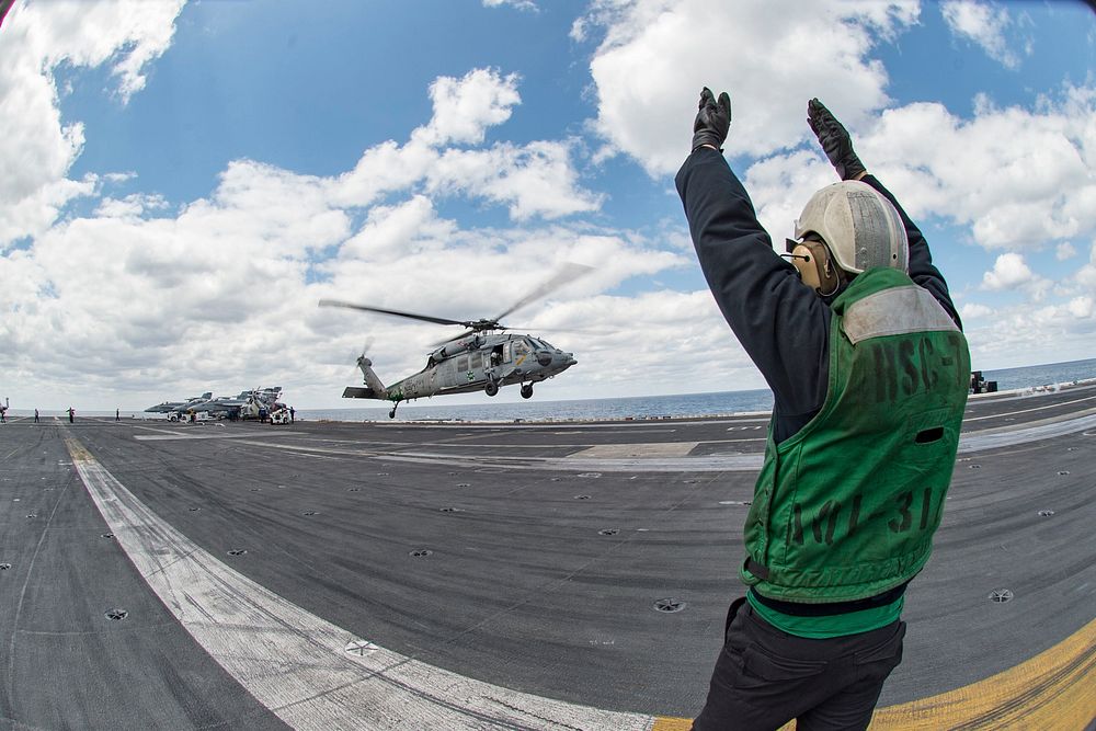 U.S. Navy Airman Brandon Robertson, assigned to the Helicopter Sea Combat Squadron (HSC) 7, signals to an MH-60S Seahawk…