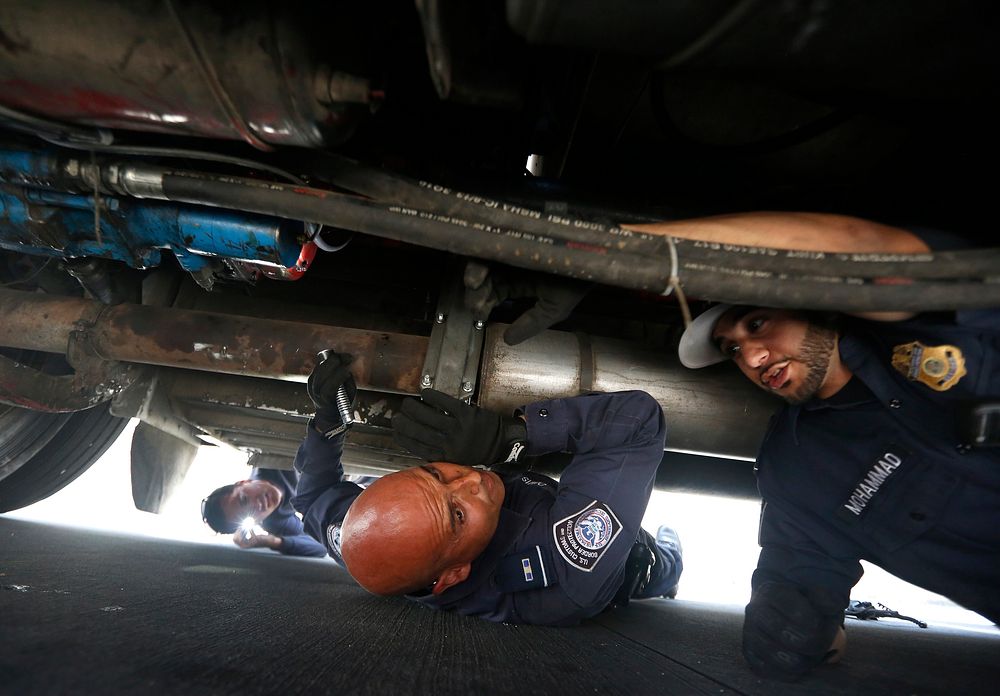 U.S. Customs and Border Protection officers inspect underneath a tractor trailer at the Otay Mesa, Calif., port of entry…