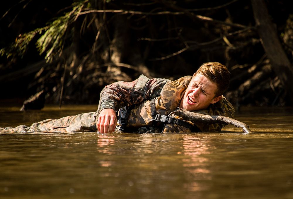 A simulated wounded 6th Ranger Training Battalion Soldier yells for help while lying in the river during a mass casualty…