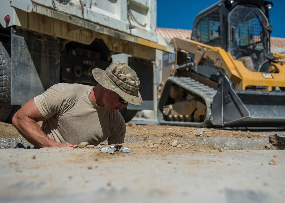 U.S. Air Force Staff Sgt. Jacob Skjei, 455th Expeditionary Civil Engineer Squadron pavements and equipment technician, digs…