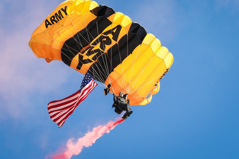 A member of the Army's Golden Knights demonstration team descends with the American flag, during a jump into a military…