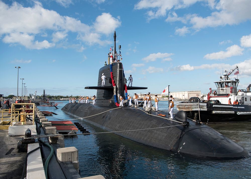Crew members aboard the Japan Maritime Self-Defense Force (JMSDF) submarine JS Unryu (SS 502) prepare the submarine to moor…