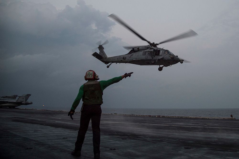 Seaman Aron Meek signals to the pilots of an MH-60S Sea Hawk helicopter assigned to the Dusty Dogs of Helicopter Sea Combat…