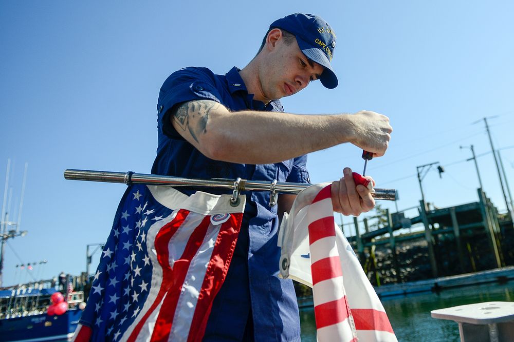 U.S. Coast Guard Petty Officer 3rd Class Ian Burgess unscrews the Coast Guard flag from the mast of a 29-foot response boat…